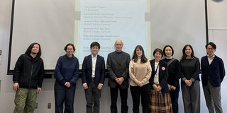 Neun Personen stehen vor einer Projektionswand