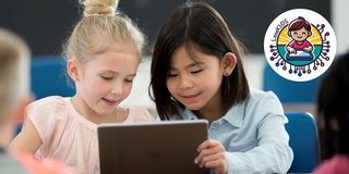 Zwei Grundschülerinnen lesen gemeinsam an einem Tablet.