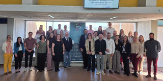 Teilnehmende des CIRCLE-Kick-Offs in Athen neben einem Roll-Up mit Informationen zu dem Projektstart 