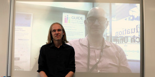 Sebastian Vogel steht vor einem Zoom Bildschirm, auf dem Prof. Dr. Gary Pollock zu sehen ist