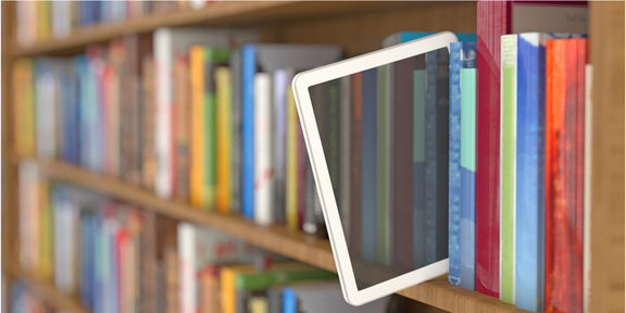 Ein Tablet Computer schaut aus einem Bücherregal hervor.