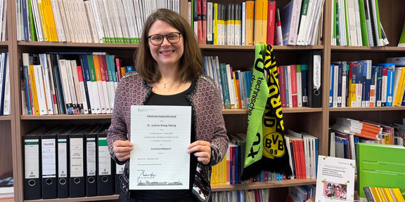 Justine Stang-Rabrig startet als Juniorprofessorin und präsentiert ihre Urkunde.