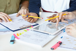 On a table are pads and sheets, a tray used by one hand.